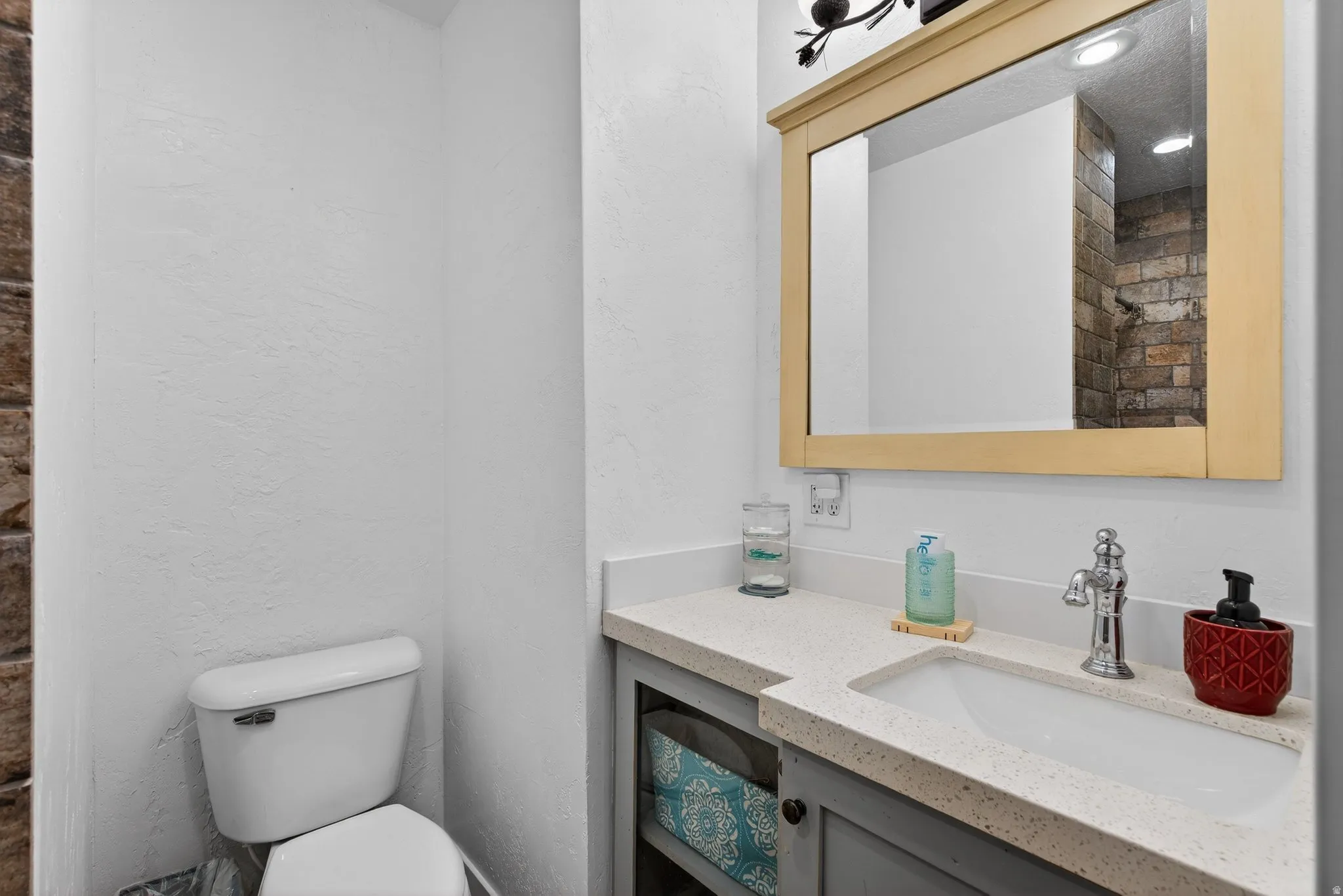 Half bathroom featuring vanity and a textured wall