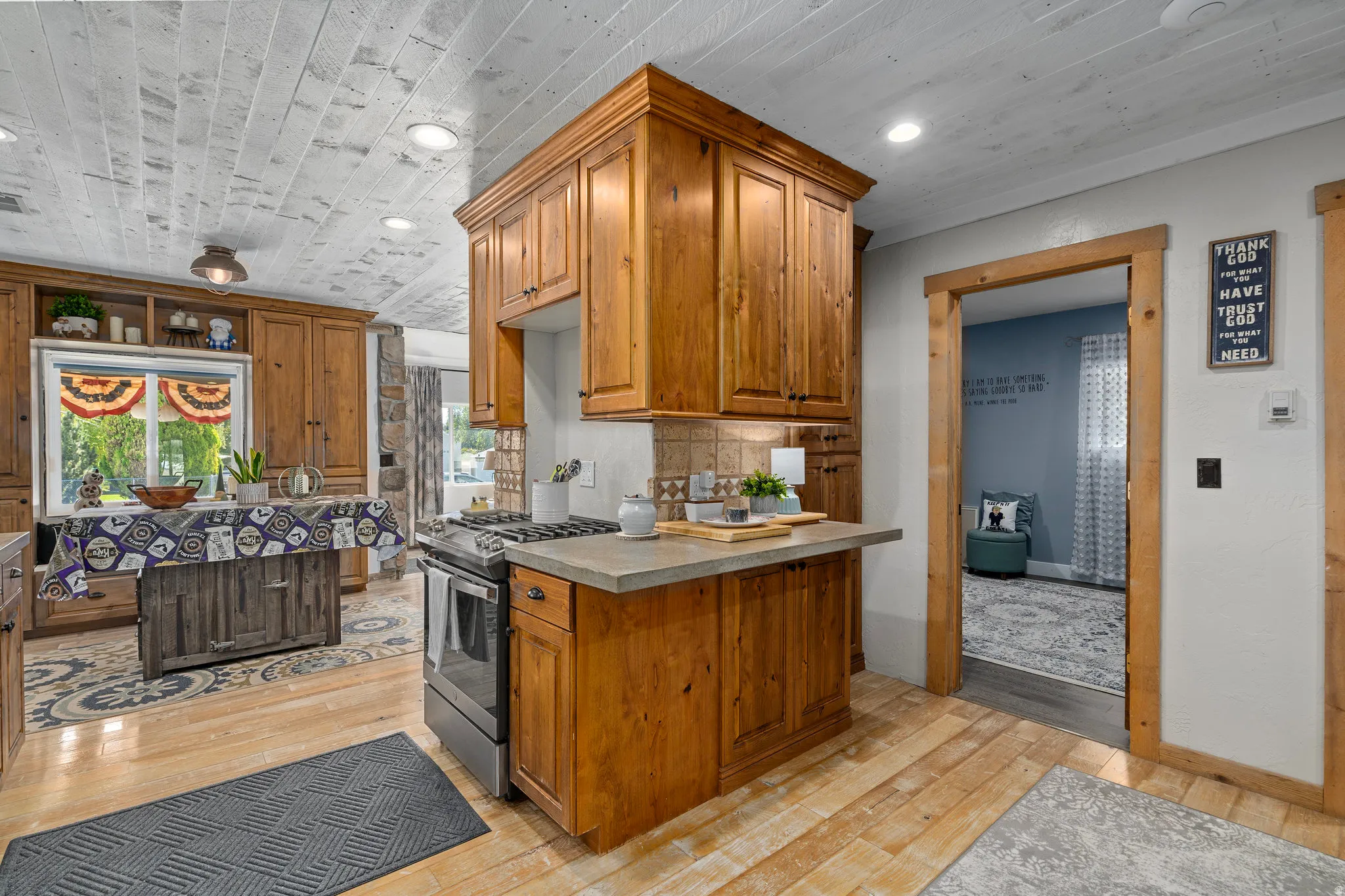 Kitchen featuring wood finish cabinets, stainless steel range with gas stovetop, light wood finished floors, light countertops, and recessed lighting