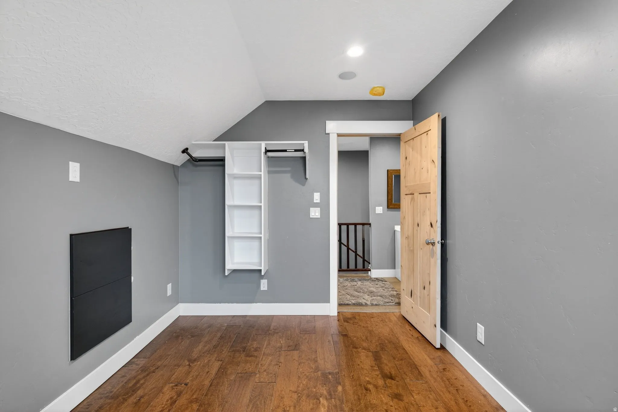 Empty room with dark wood-style floors and vaulted ceiling