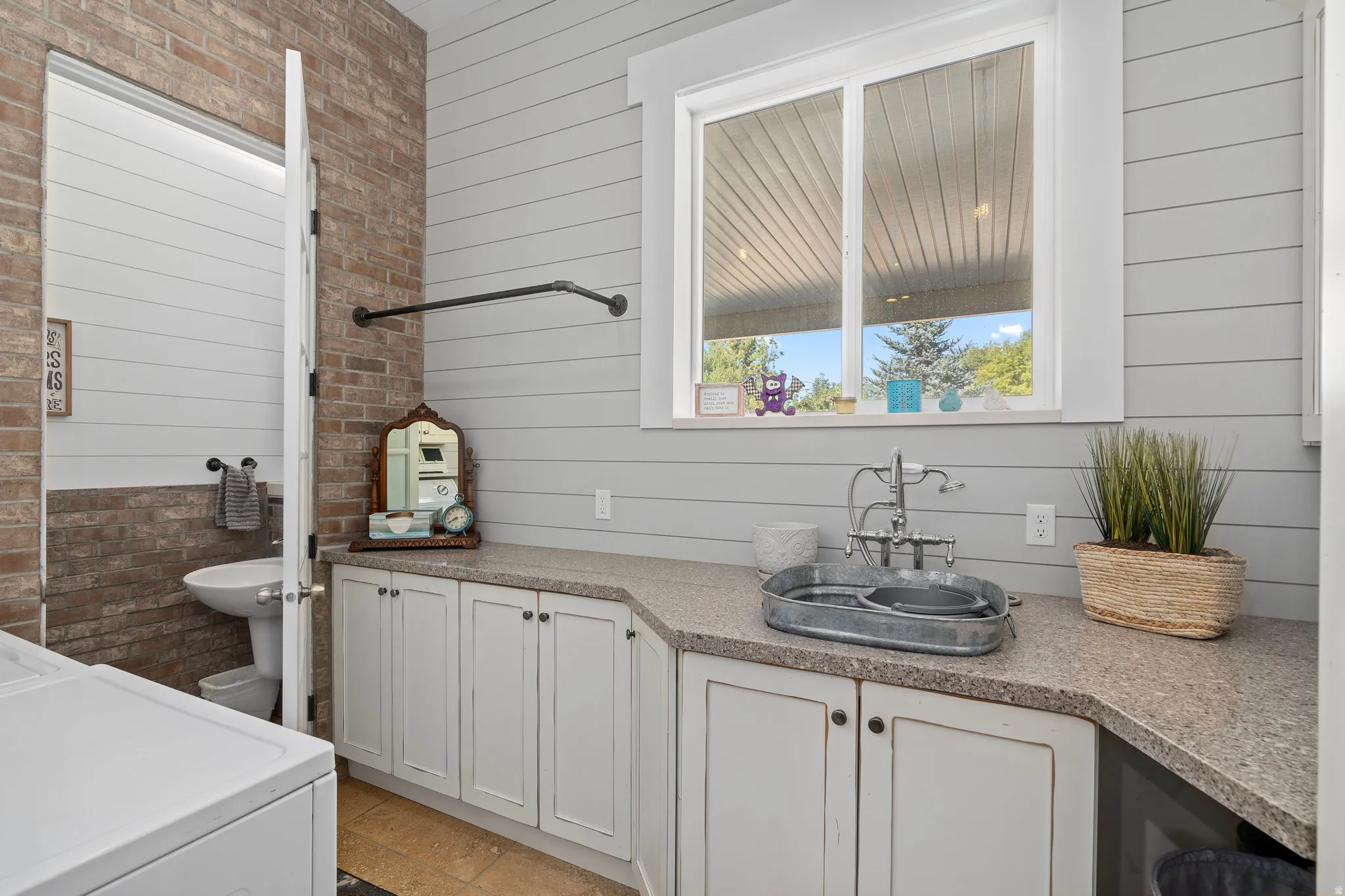 Full bathroom with washer / dryer, vanity, wooden walls, and brick wall