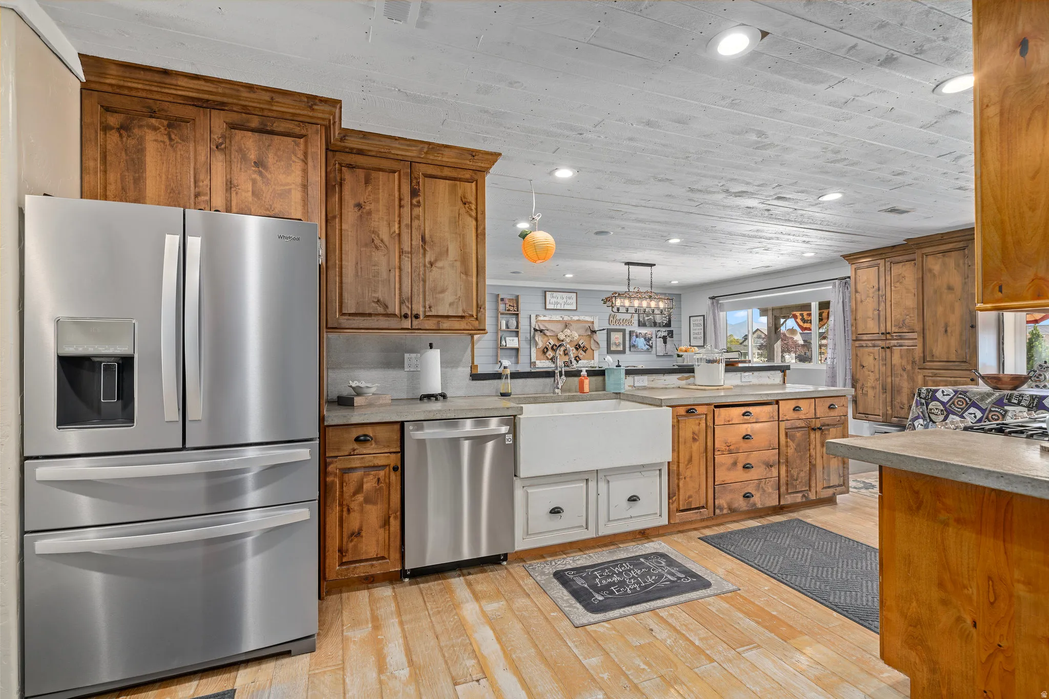 Kitchen with wood finish cabinets, stainless steel appliances, light countertops, wood ceiling, and light wood-style flooring
