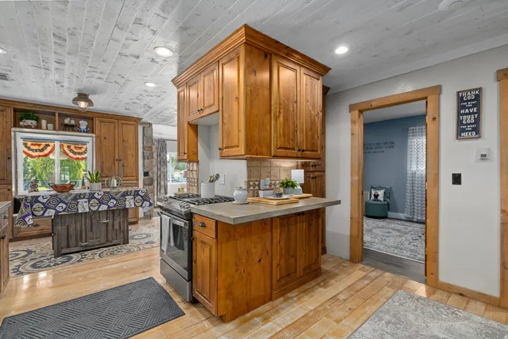 Kitchen featuring wood finish cabinets, stainless steel range with gas stovetop, light wood finished floors, light countertops, and recessed lighting