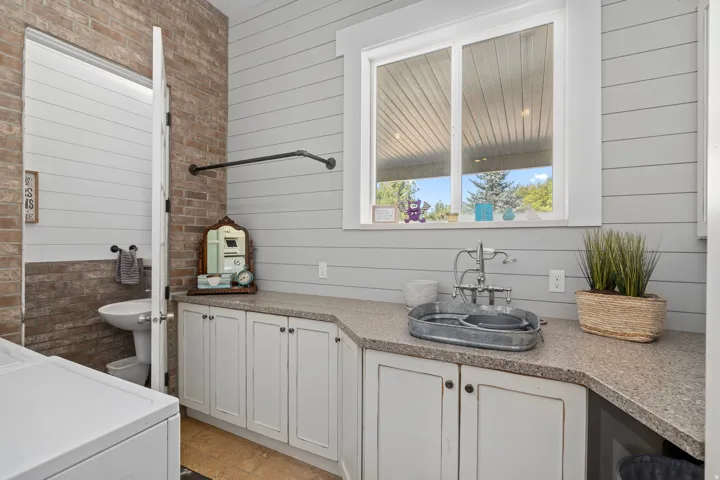 Full bathroom with washer / dryer, vanity, wooden walls, and brick wall