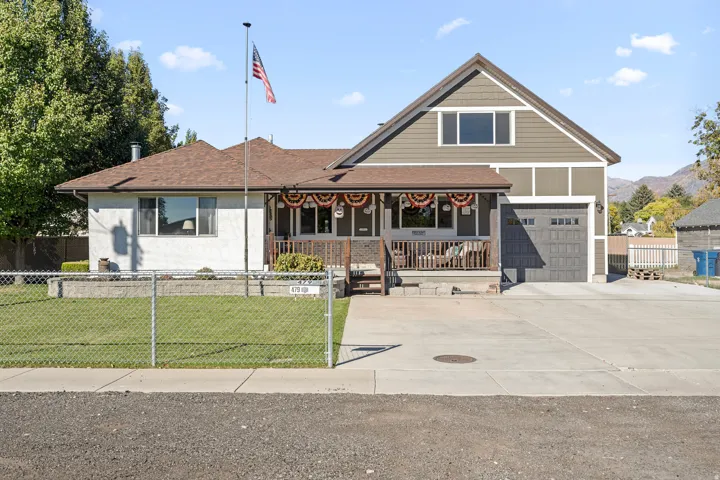View of front of home featuring covered porch, a fenced front yard, roof with shingles, and driveway