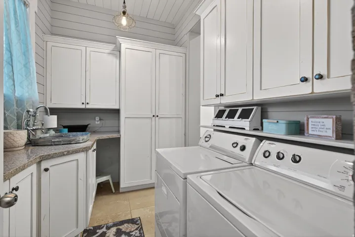 Laundry room featuring independent washer and dryer, cabinet space, and light tile patterned floors