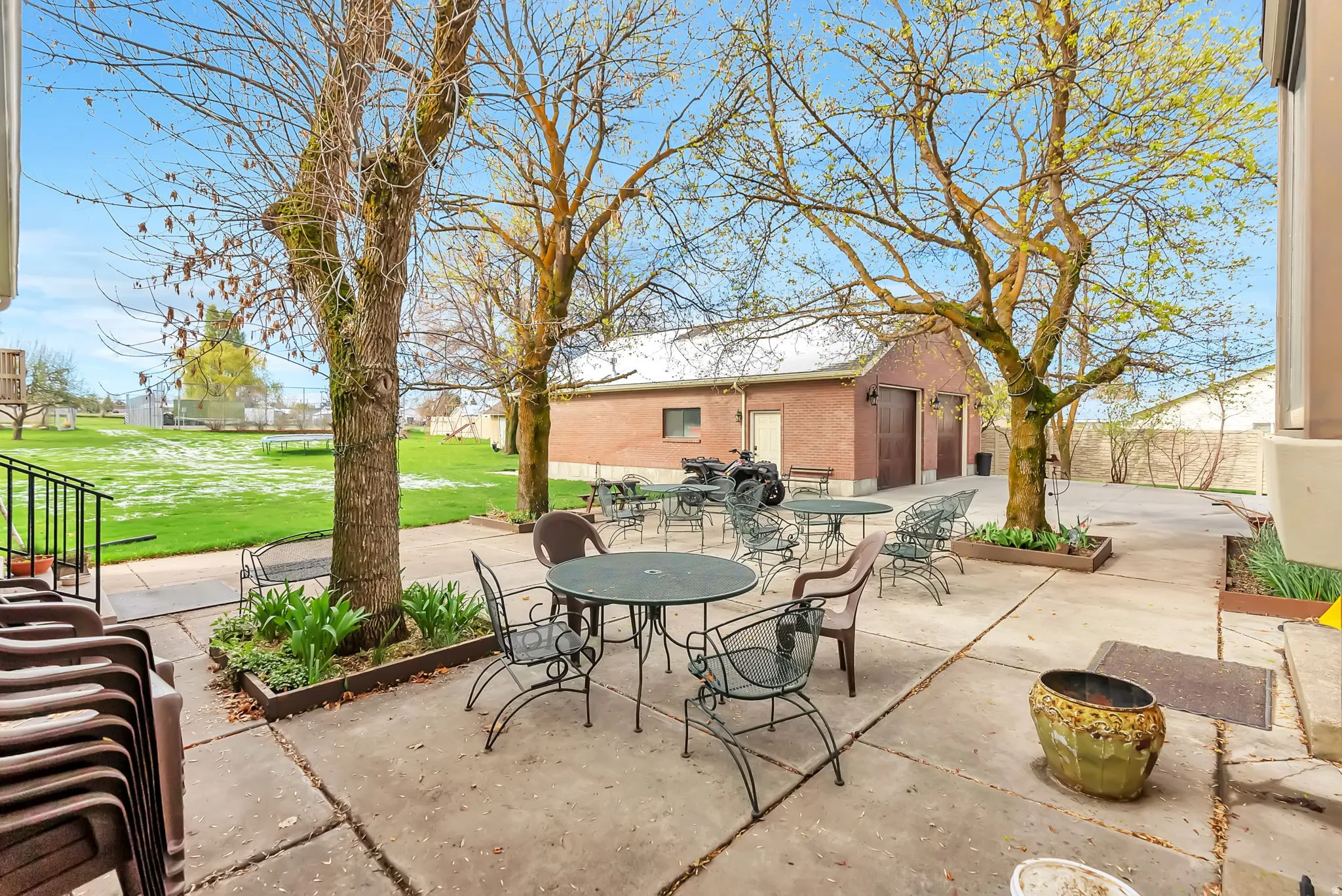 View of patio featuring outdoor dining space and view of detached 2 car garage with vault.