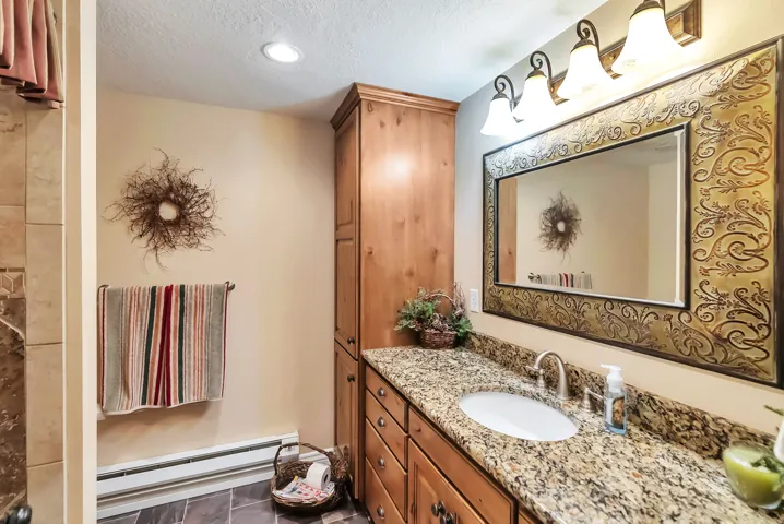 Bathroom featuring a baseboard radiator, vanity, a textured ceiling, and recessed lighting