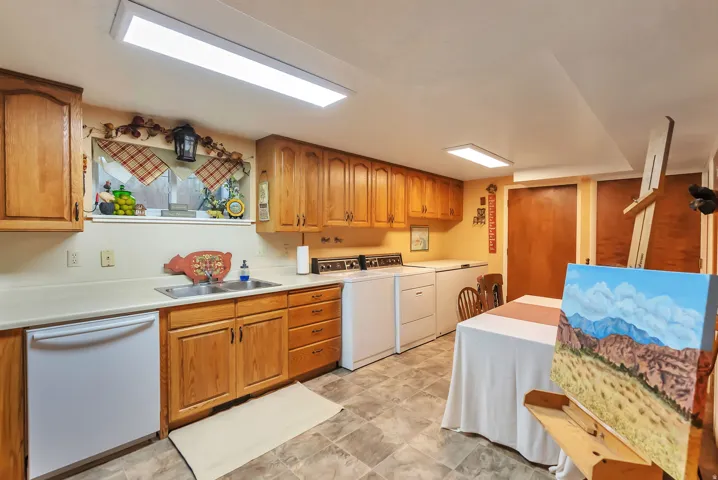 Kitchen with wood finish cabinetry, dishwasher, light countertops, and washer and dryer