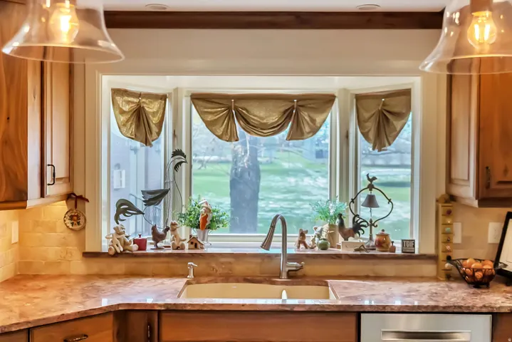 Kitchen bay window featuring wood finish cabinetry, dishwasher, and light stone counters