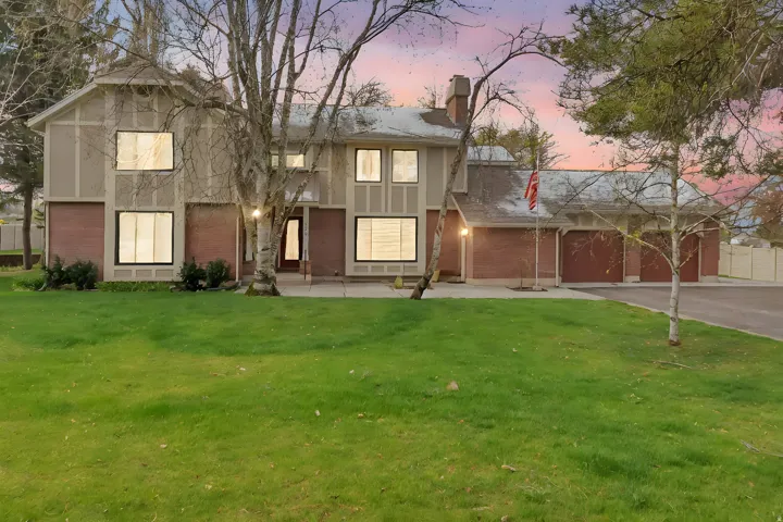 View of front of house with brick siding, driveway, a chimney, and a lawn