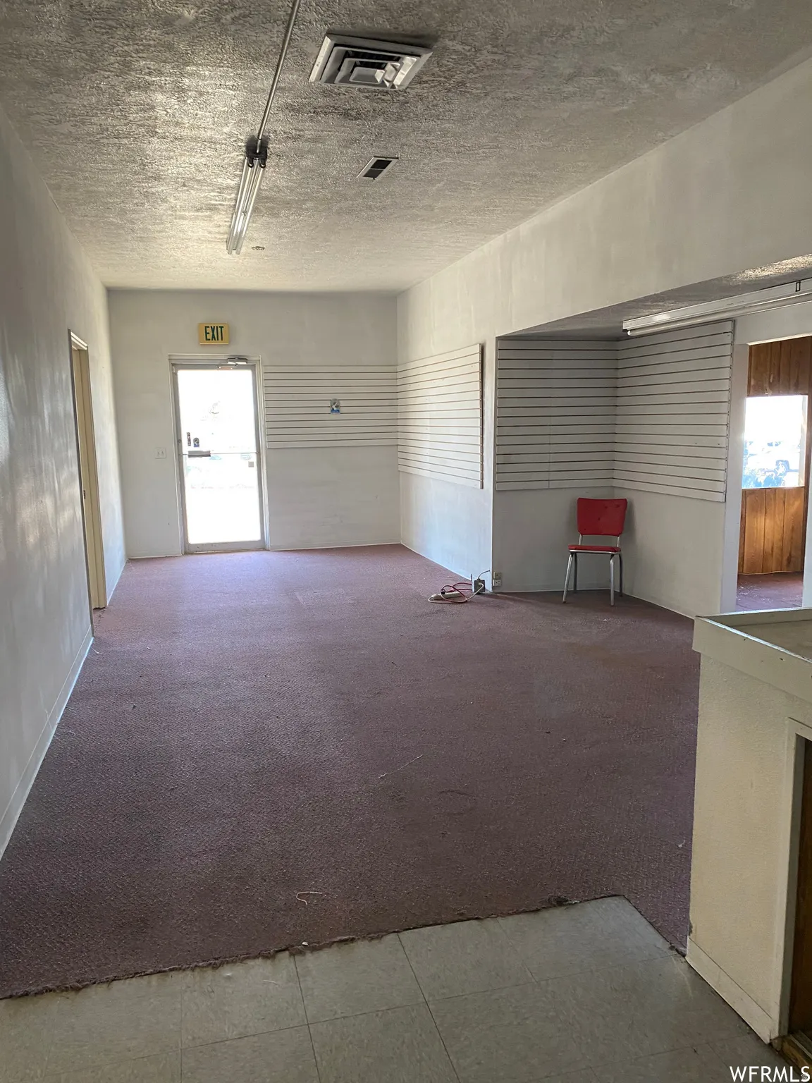 Unfurnished room with healthy amount of natural light, light carpet, and a textured ceiling