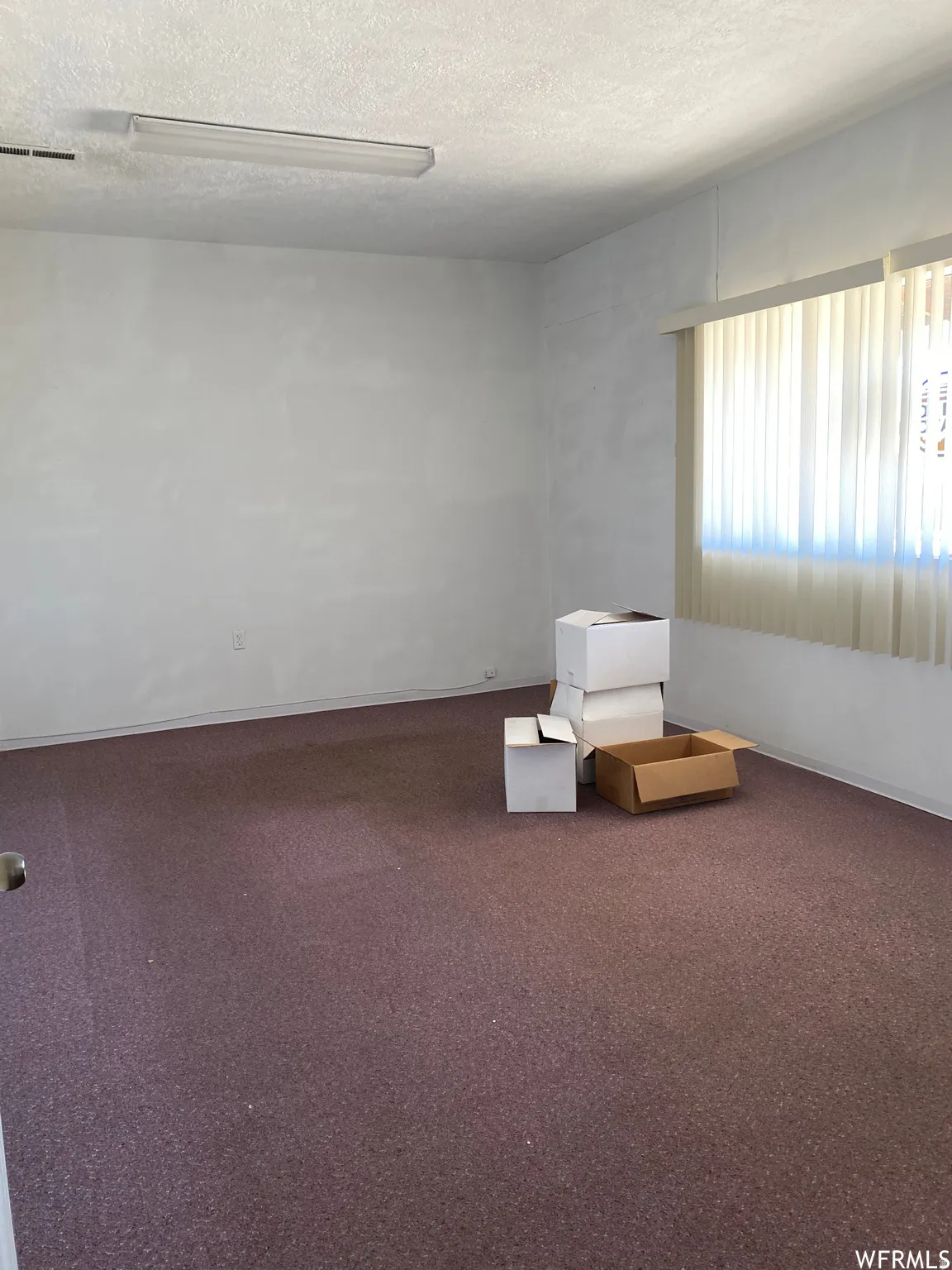 Unfurnished room with a textured ceiling and carpet flooring
