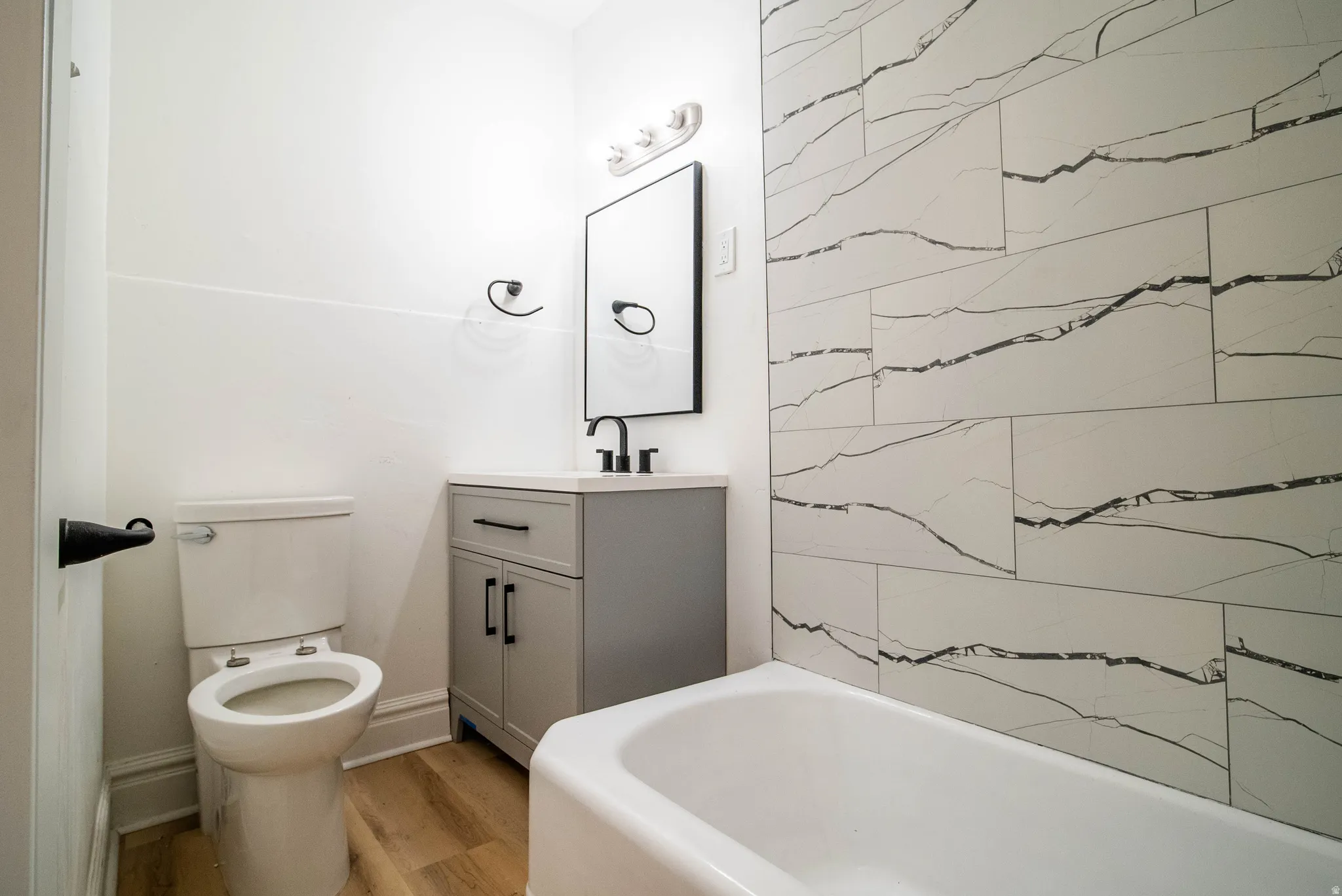 Bathroom featuring vanity, light wood finished floors, and washtub / shower combination