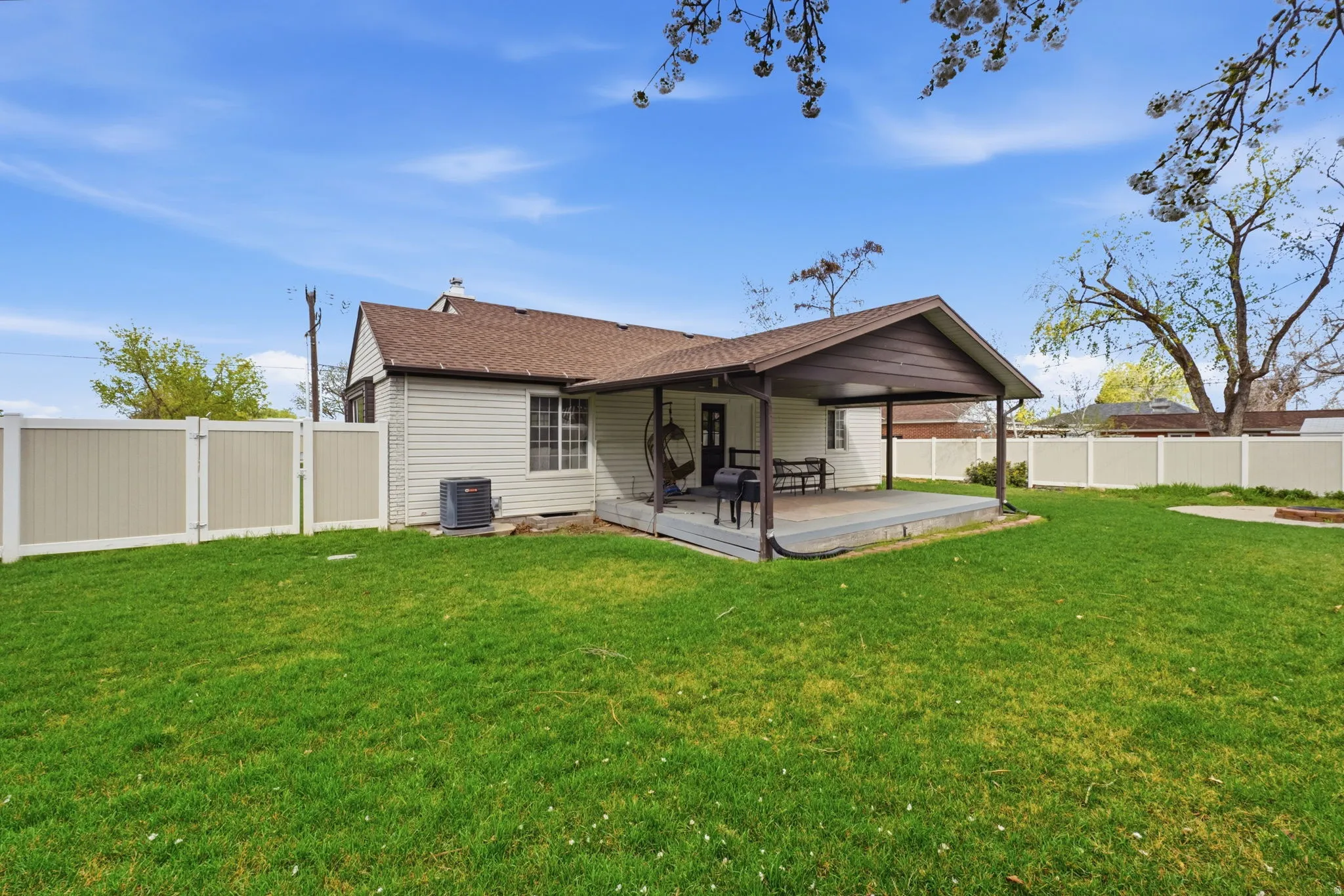 Back of property featuring a fenced backyard, a gate, a deck, and roof with shingles