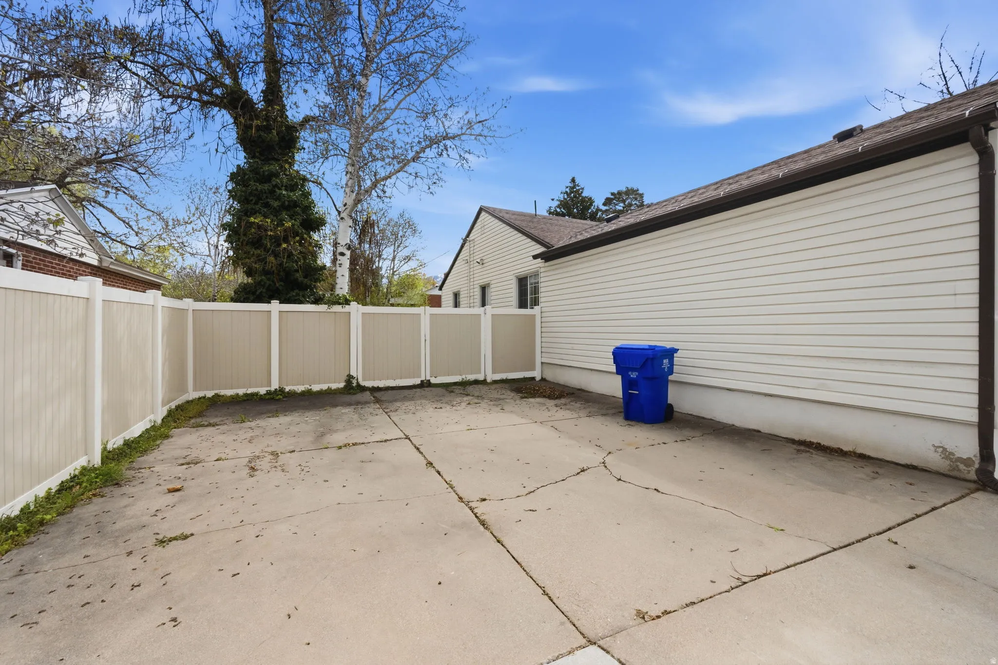 View of side of home with a patio area, a fenced backyard, and a shingled roof