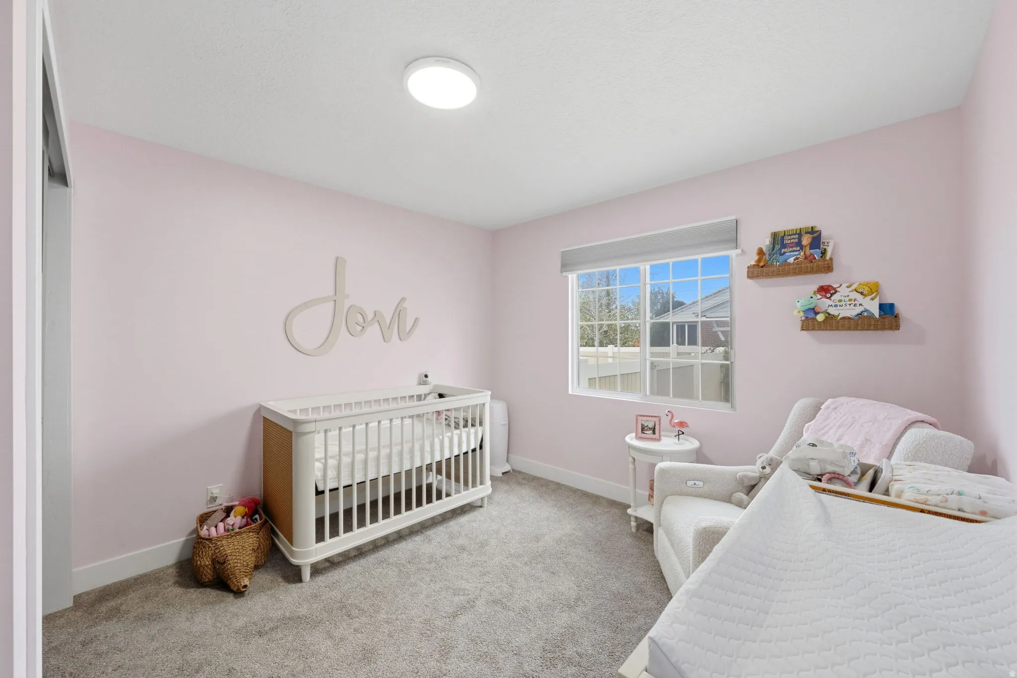 Bedroom with a nursery area and light colored carpet