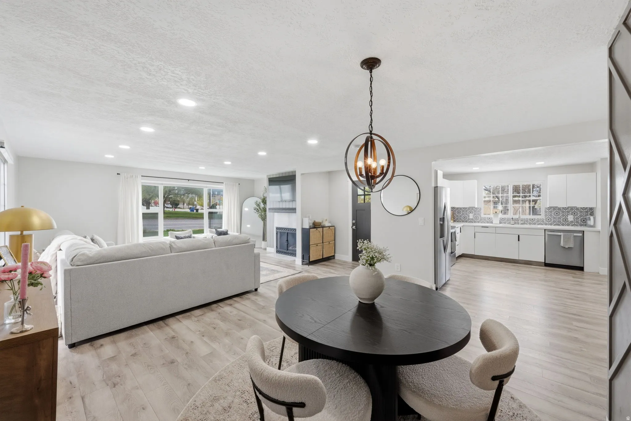 Dining space featuring a textured ceiling, light wood-style flooring, hanging lights, and a fireplace