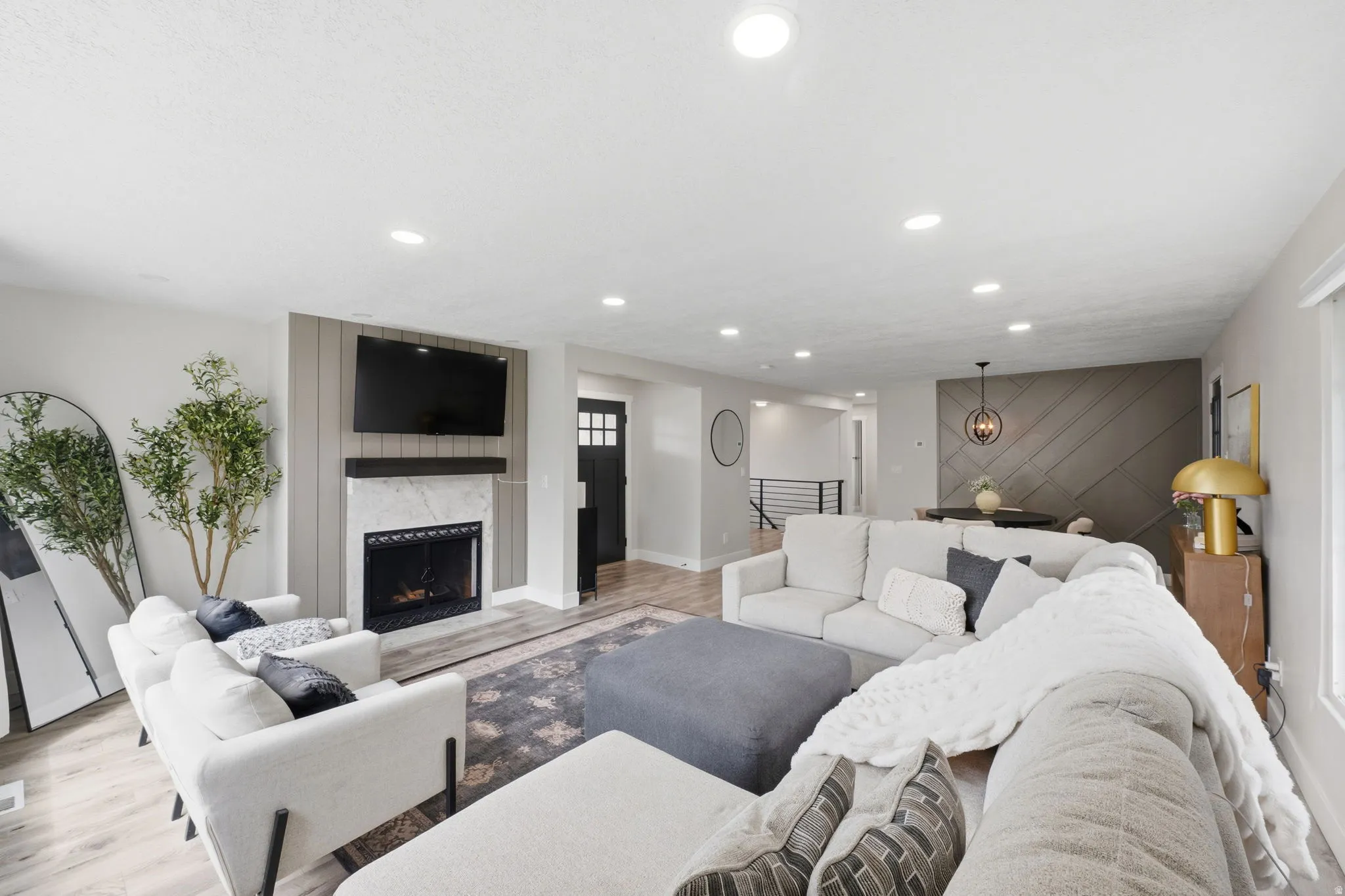 Living area featuring light wood finished floors, an accent wall, a fireplace, and recessed lighting