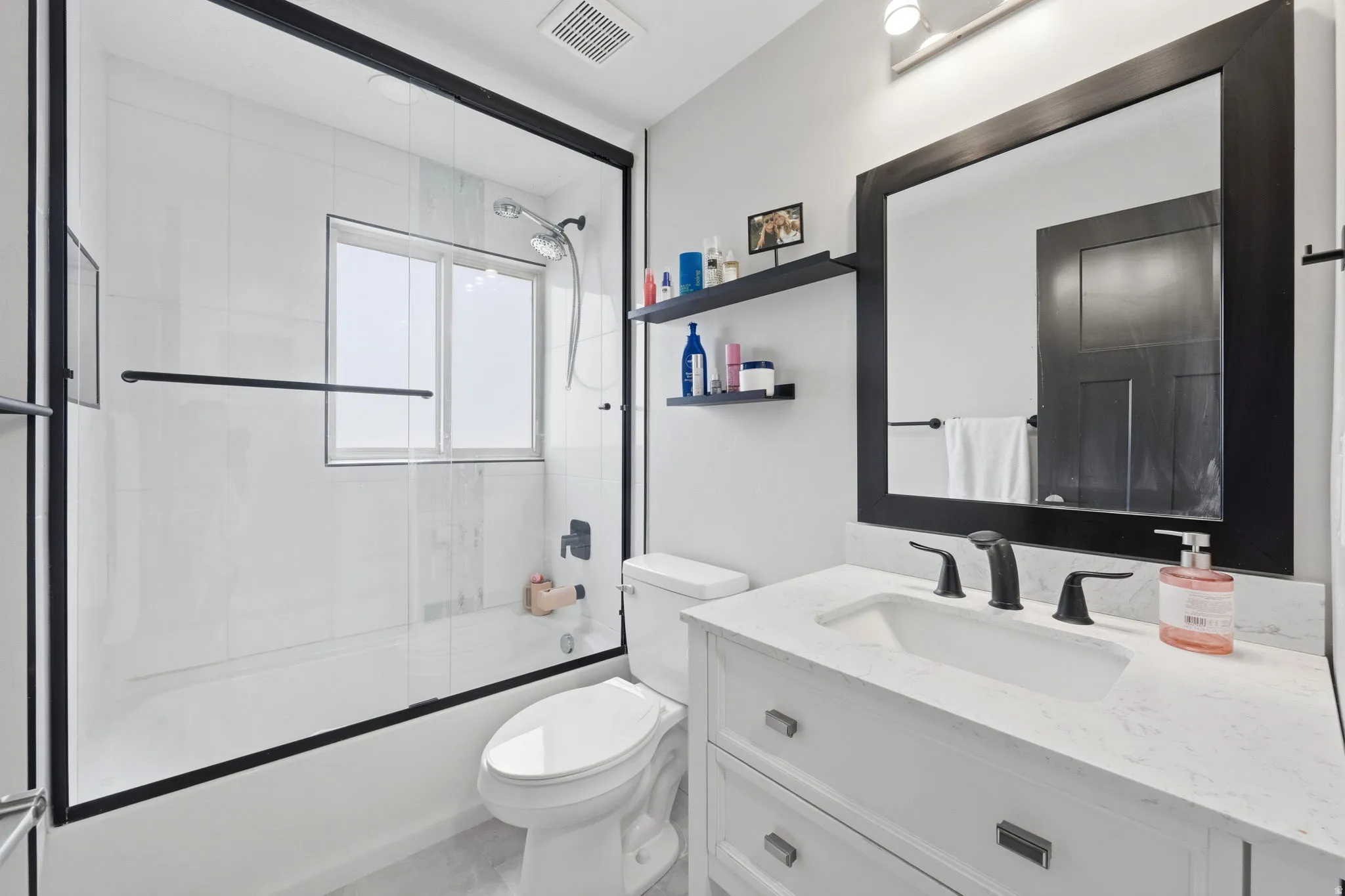 Bathroom featuring vanity and enclosed tub / shower combo