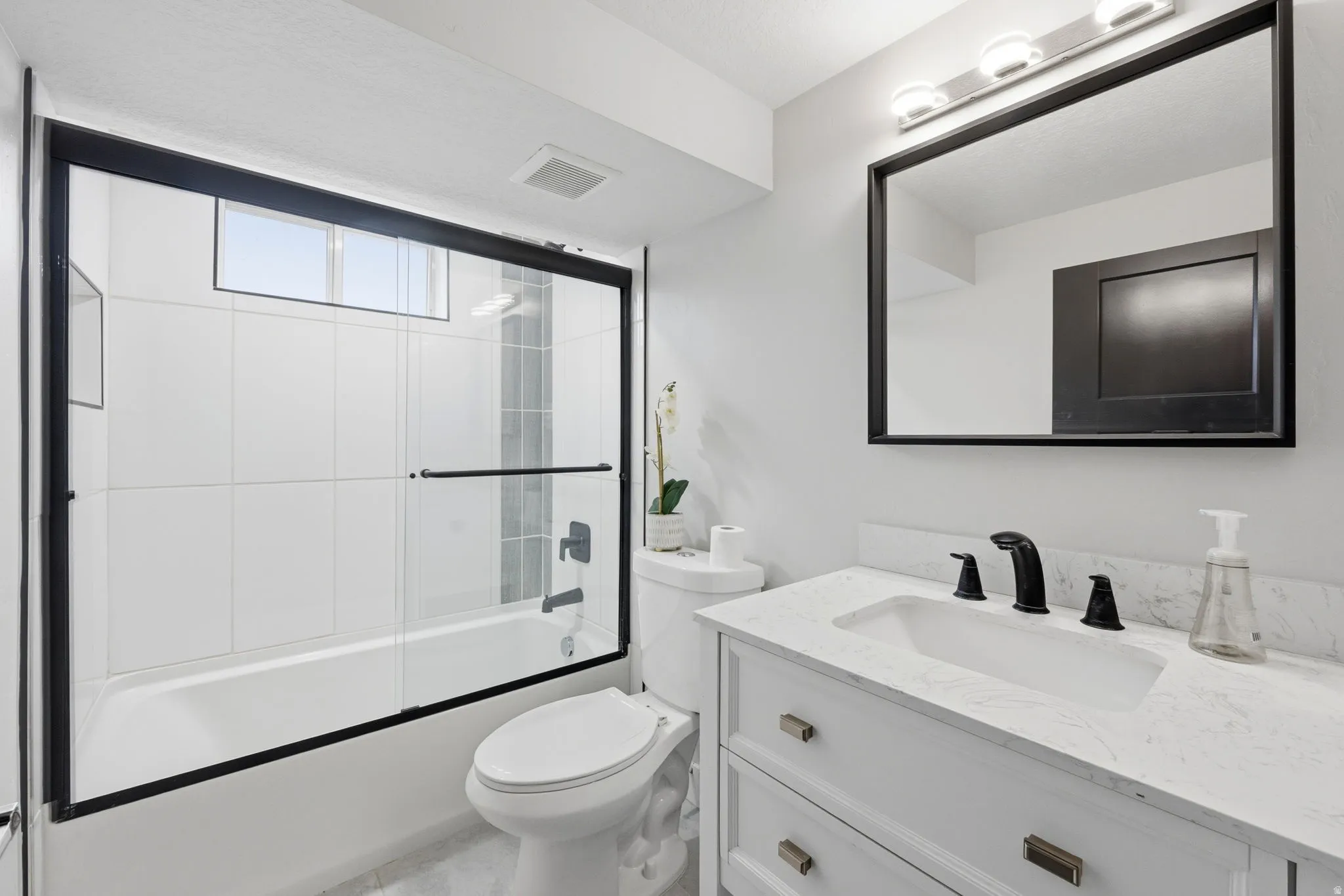 Bathroom with vanity and bath / shower combo with glass door
