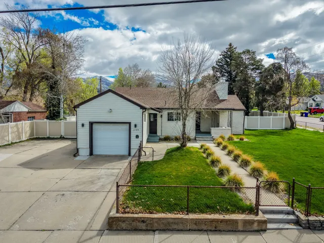 Ranch-style home featuring a fenced front yard, a gate, driveway, a garage, and a chimney