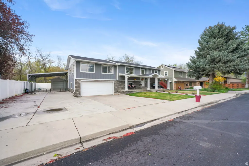 Traditional-style home with an attached garage, concrete driveway, stone siding, board and batten siding, and covered porch