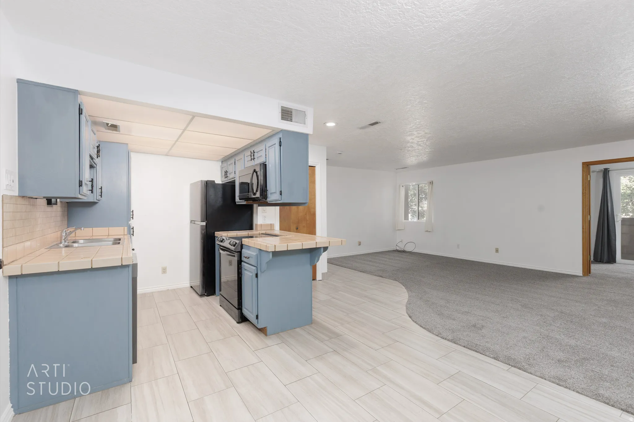 Kitchen featuring tile counters, open floor plan, blue cabinets, and plenty of natural light
