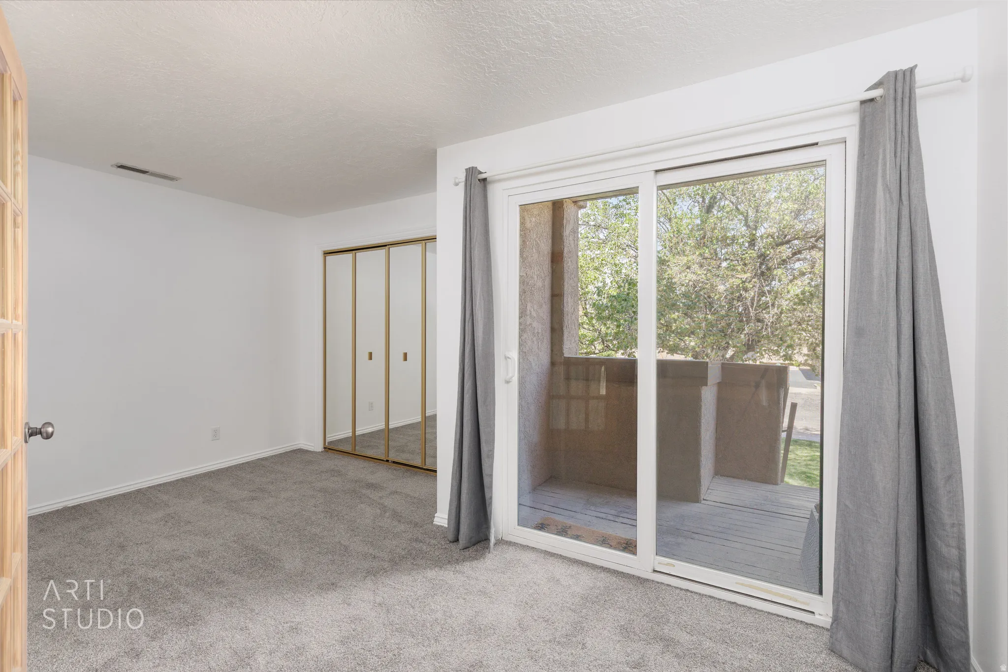 Unfurnished bedroom featuring light colored carpet, access to exterior, a closet, and a textured ceiling