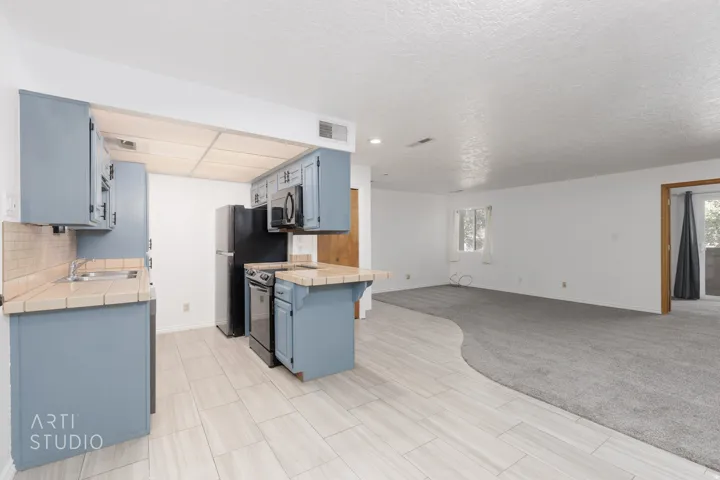 Kitchen featuring tile counters, open floor plan, blue cabinets, and plenty of natural light