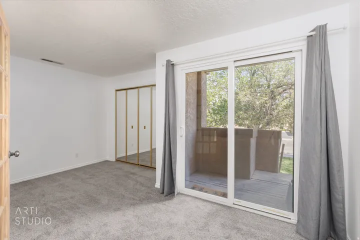 Unfurnished bedroom featuring light colored carpet, access to exterior, a closet, and a textured ceiling