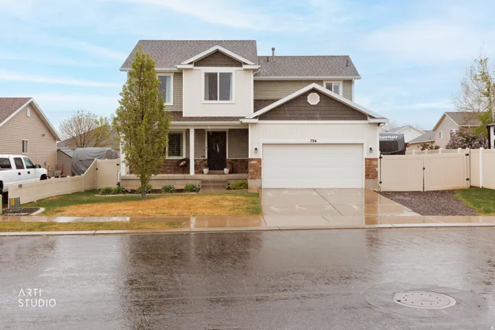 View of front of house with driveway, stone siding, covered porch, board and batten siding