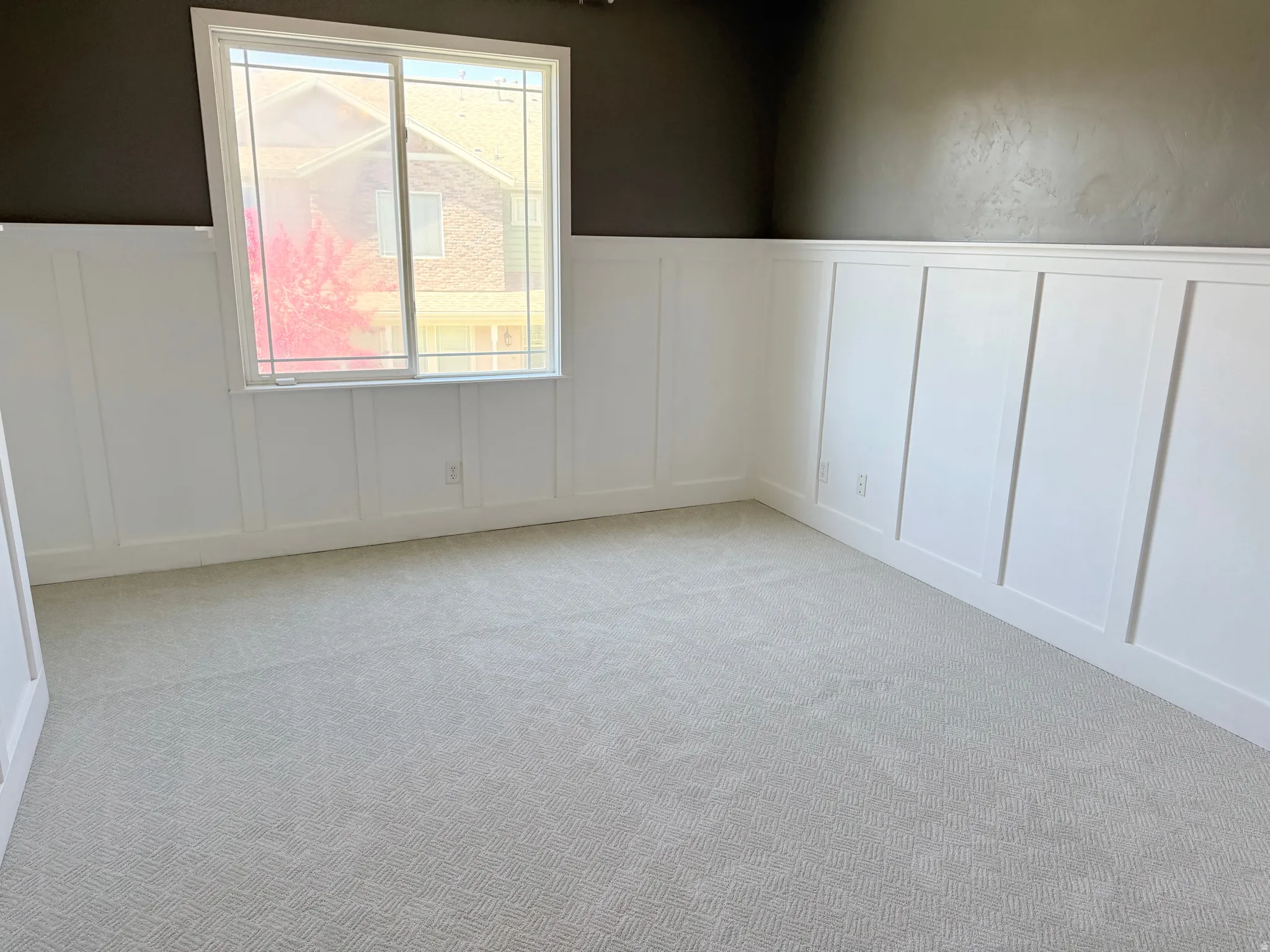 Unfurnished room with a decorative wall, wainscoting, and light colored carpet