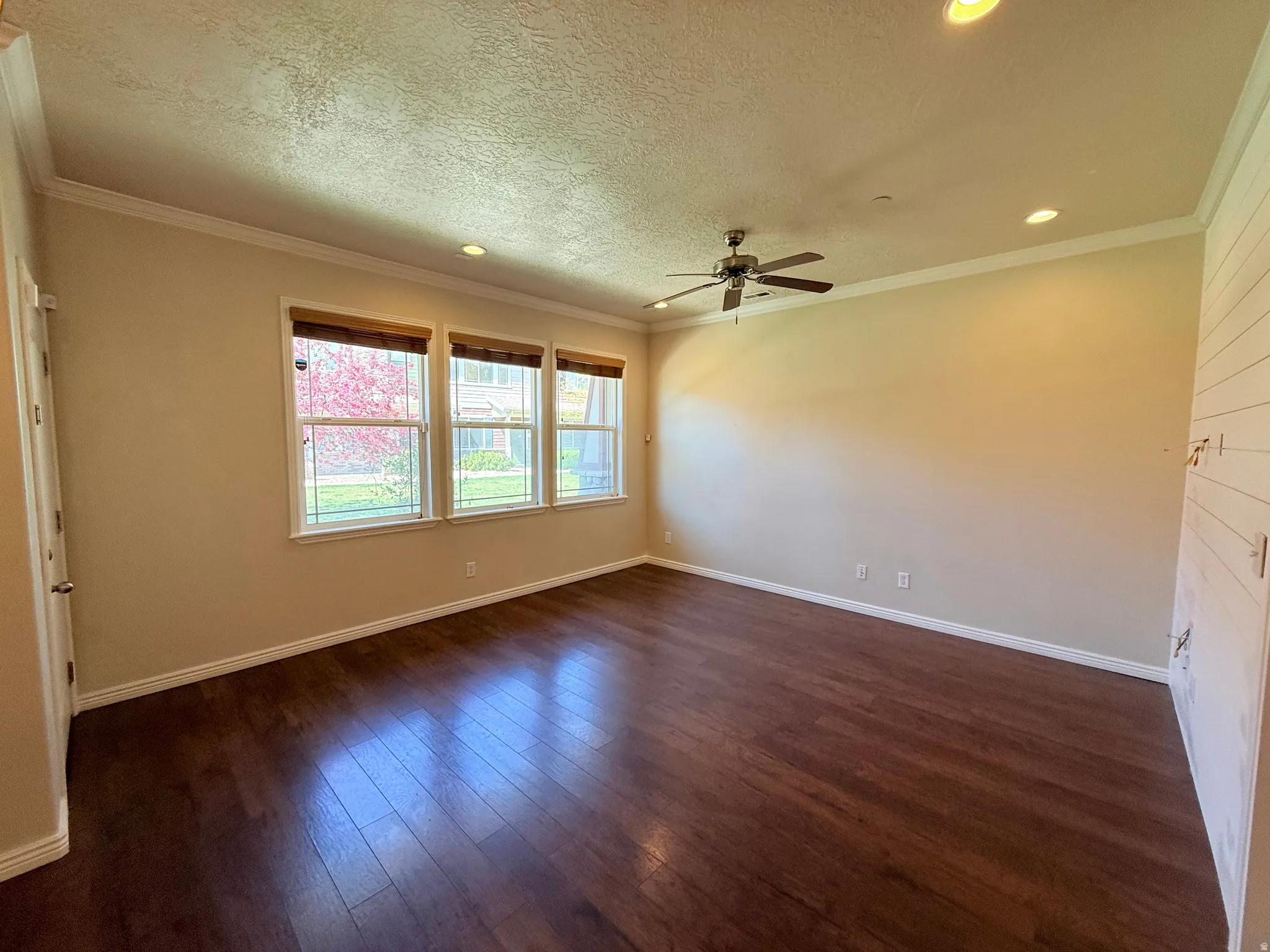 Empty room featuring dark wood-style floors, a textured ceiling, recessed lighting, a ceiling fan, and crown molding