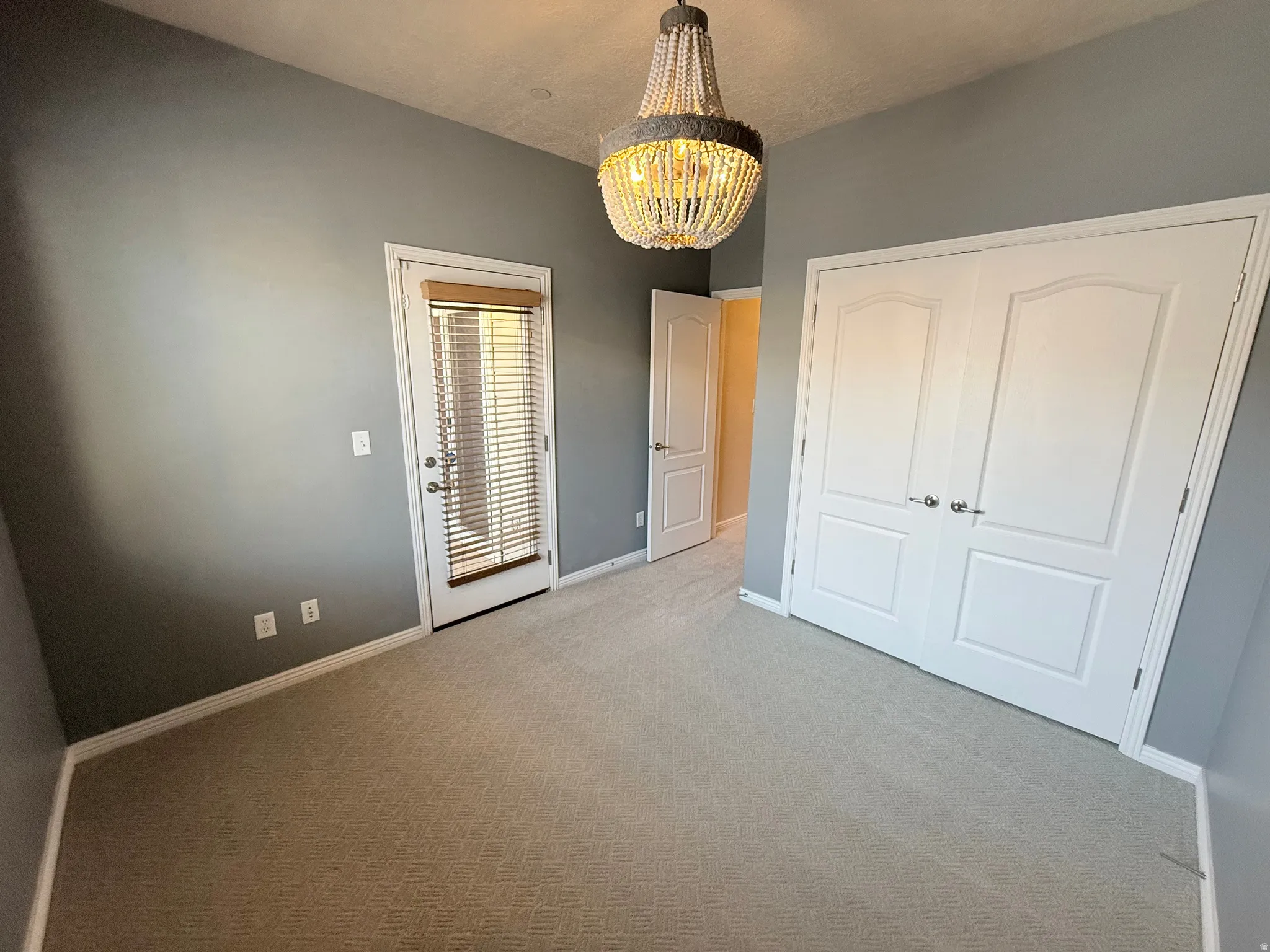 Unfurnished bedroom with light carpet, suspended lighting, and a closet