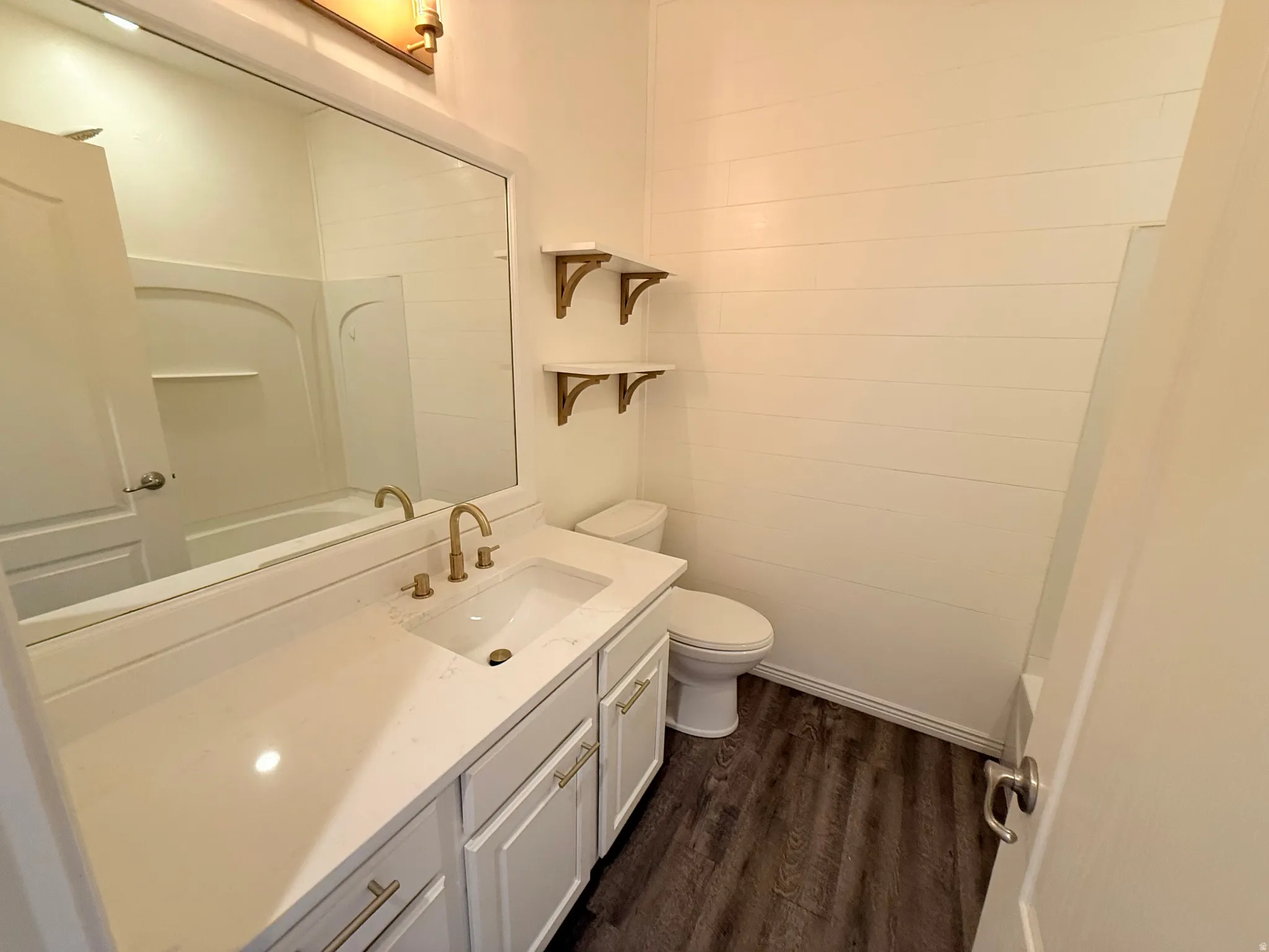 Bathroom with vanity, dark wood finished floors, and washtub / shower combination