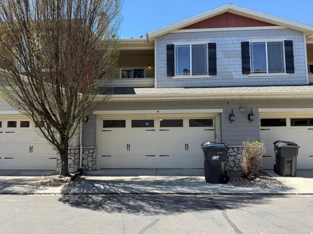 View of front of house with a shingled roof, an attached garage, and driveway