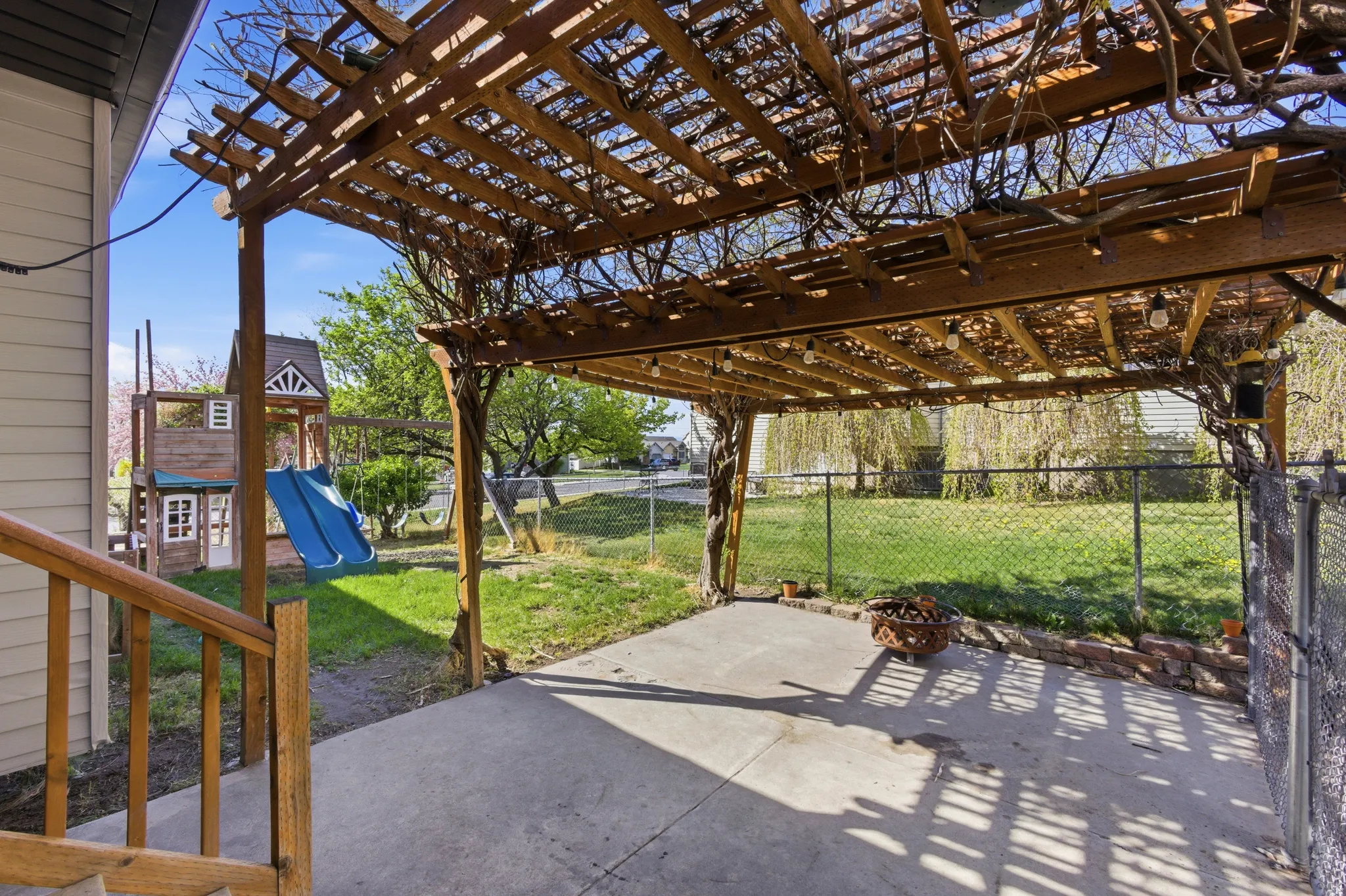 Fenced backyard featuring a patio, a playground, and pergola