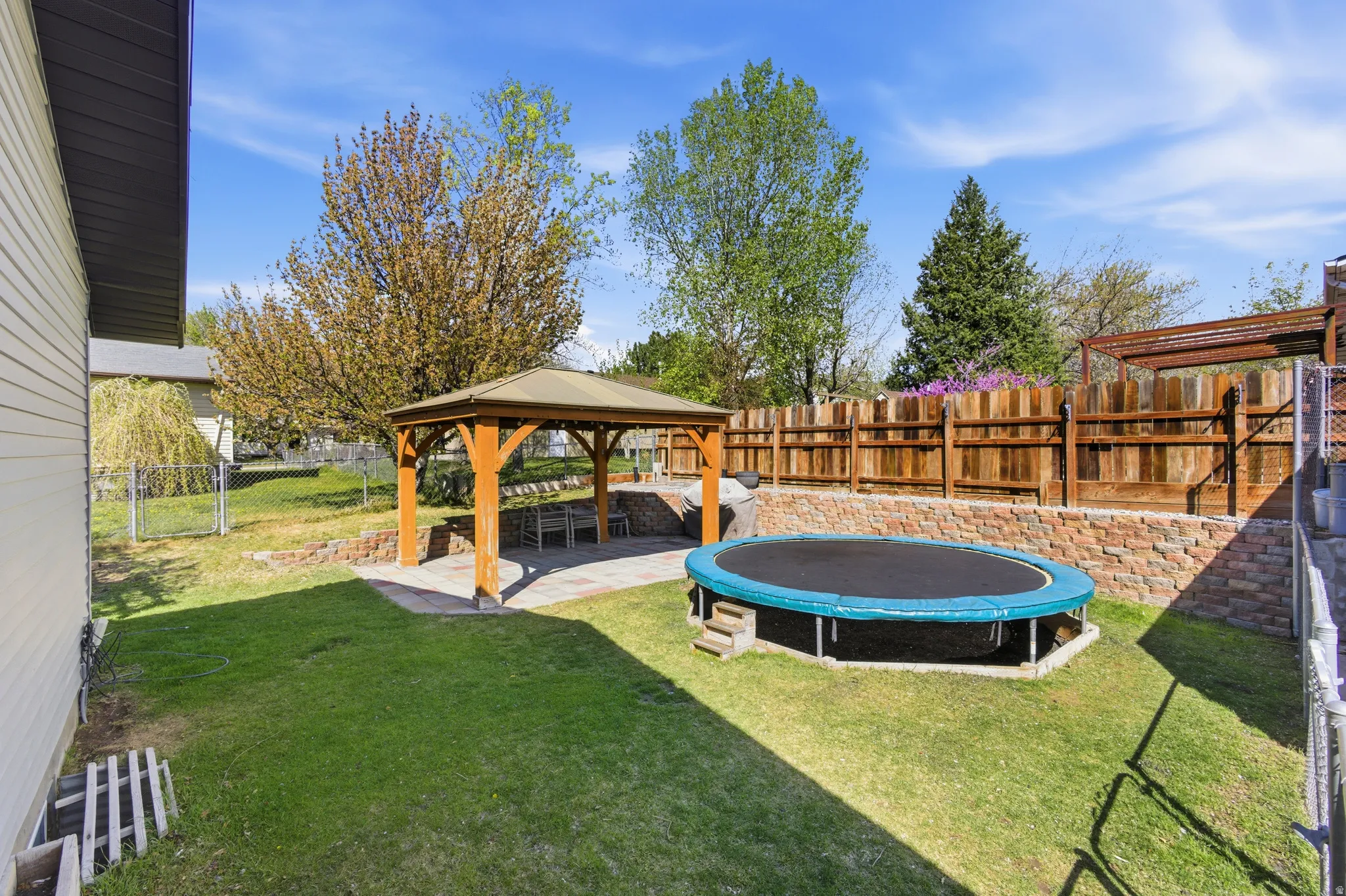 Fenced backyard featuring a patio, a gazebo, and a trampoline