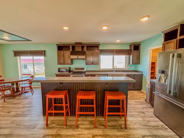 Kitchen featuring open shelves, a breakfast bar area, stainless steel appliances, light wood finished floors, and a center island