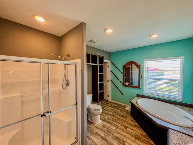 Bathroom featuring a shower stall, a bath, wood finished floors, and recessed lighting