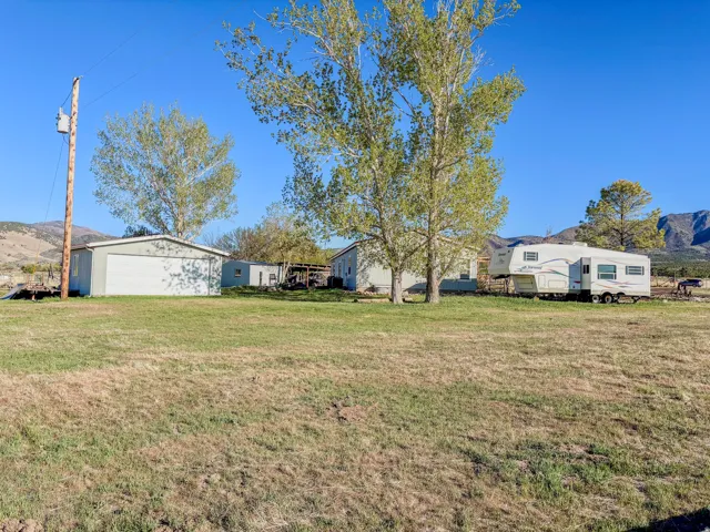 View of grassy yard with a mountain view, an outdoor structure, and a garage