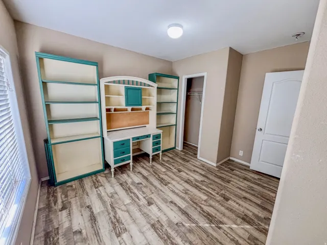 Bedroom featuring light wood-style floors, a desk, and a closet