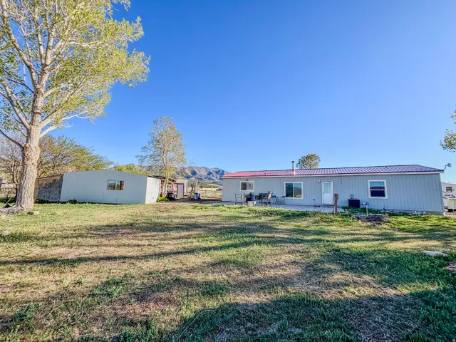 Back of house with a lawn, a patio area, a metal roof, and a mountain view