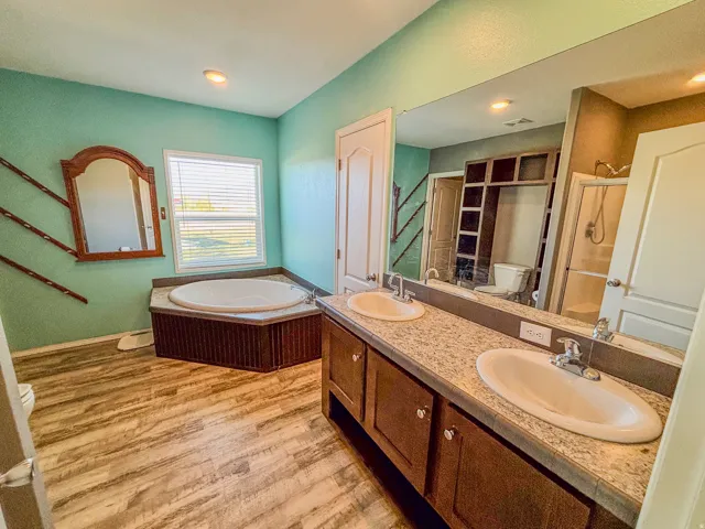 Full bath featuring double vanity, a garden tub, light wood finished floors, and a shower stall