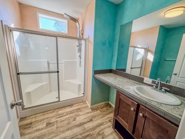 Full bath with a shower stall, vanity, and light wood-style flooring