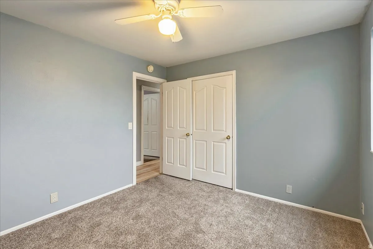 Unfurnished bedroom featuring light carpet, ceiling fan, and a closet