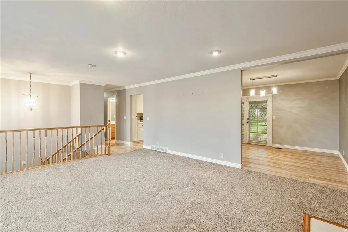 Spare room with light carpet, ornamental molding, and hanging lights