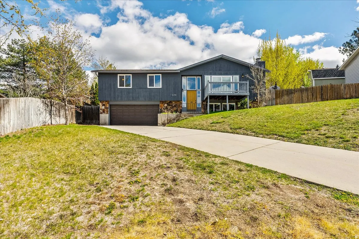 Raised ranch featuring concrete driveway, an attached garage, and a chimney