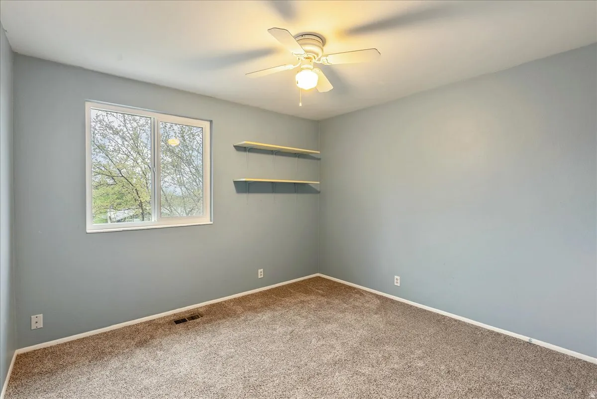 Carpeted spare room with ceiling fan and baseboards