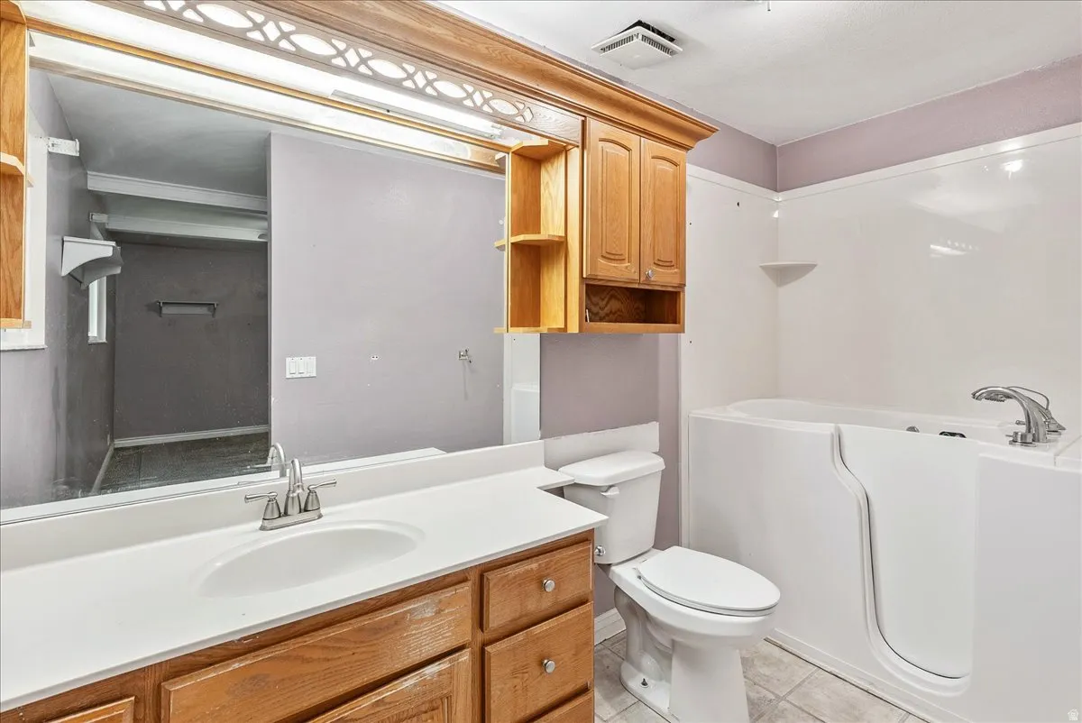 Bathroom featuring a garden tub, vanity, and light tile patterned flooring